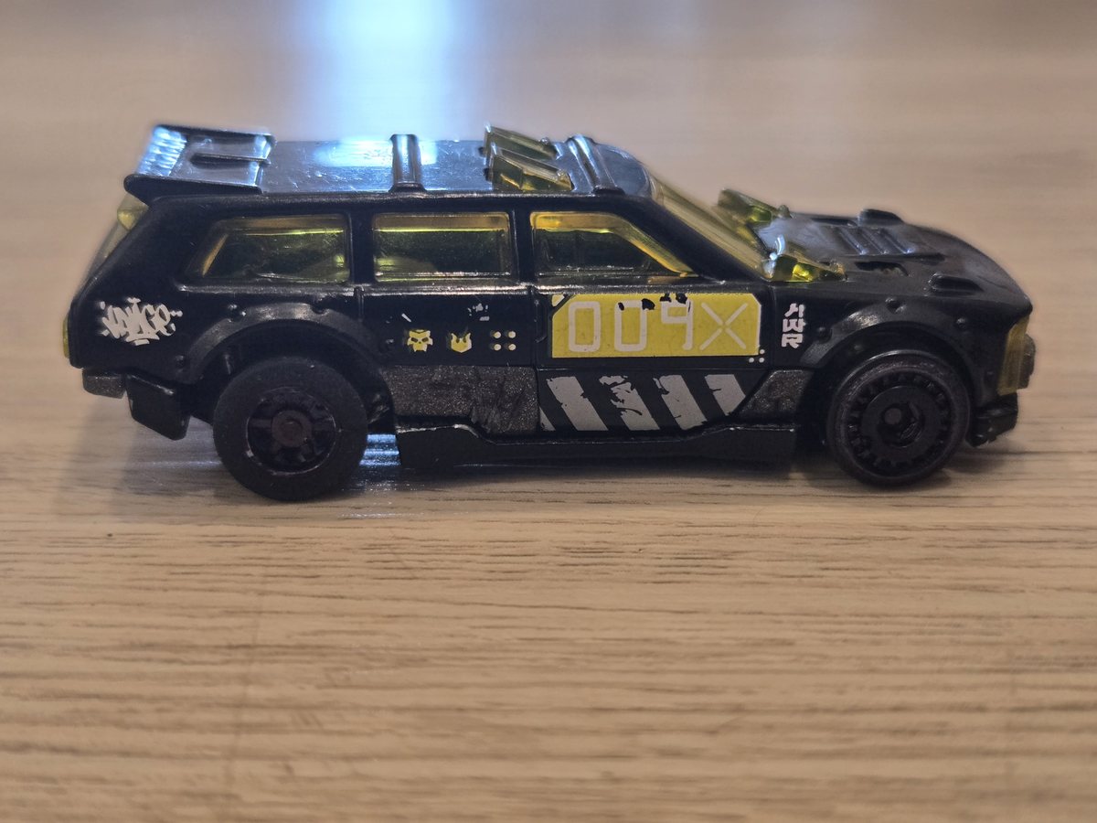 A black 1/64 diecast wagon in profile with an Ant pull-back motor built inside it
