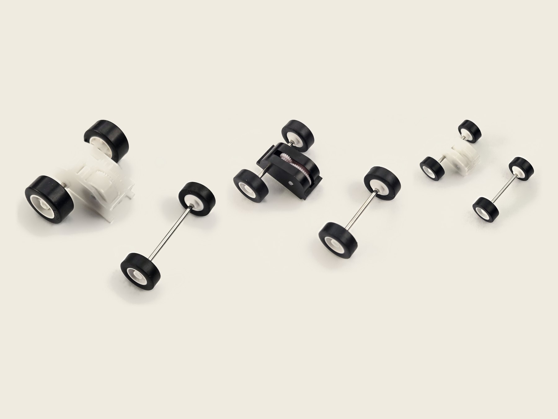 Three steel-spring pullback motors, a Brute, a Stout and an Ant, side by side largest to smallest, each with its matching front wheel-and-axle set
